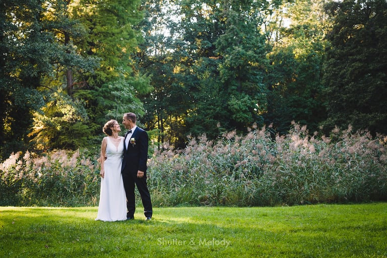 Bride and groom standing in a meadow.