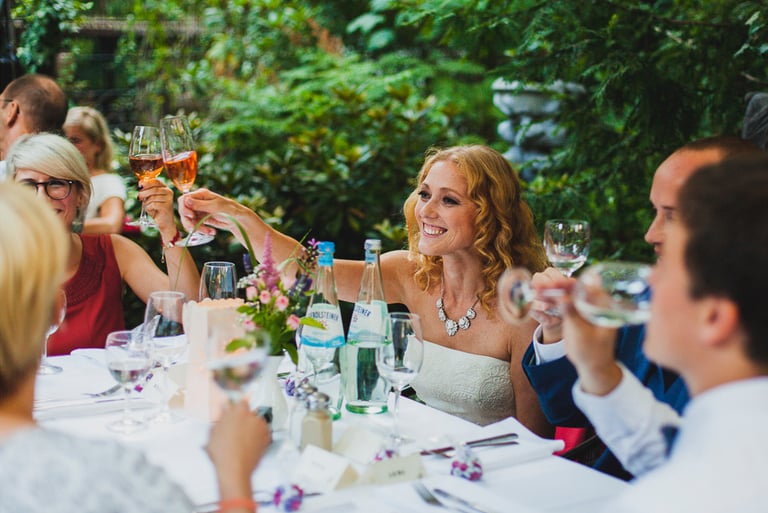 Bride toasting wedding guests at a table.