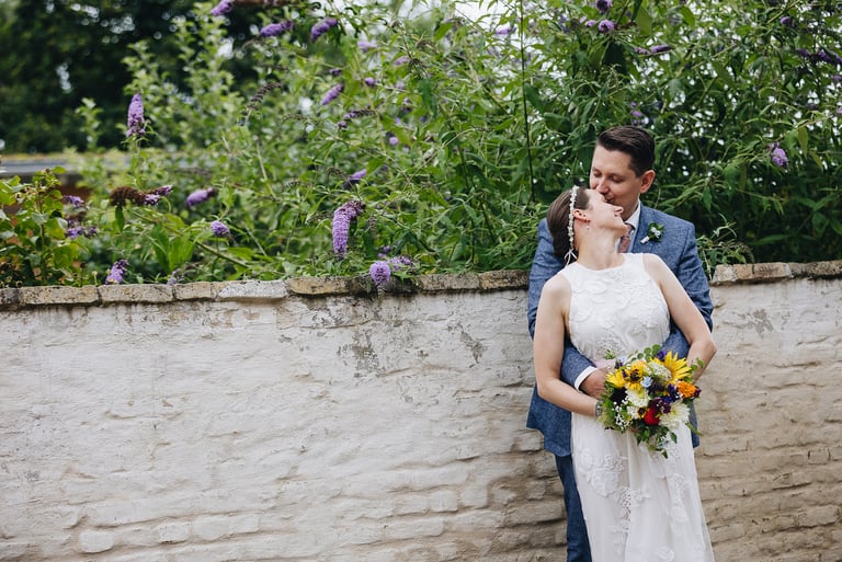 Bride and groom standing in front of a wall.