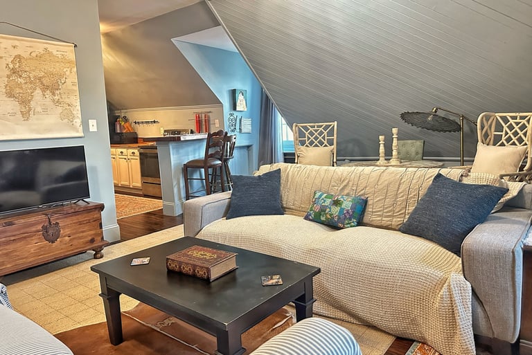 Cozy attic apartment living room with sloped ceilings, comfortable sofa, and vintage world map decor.