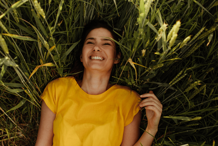 a woman in a yellow dress smiling and holding a flower