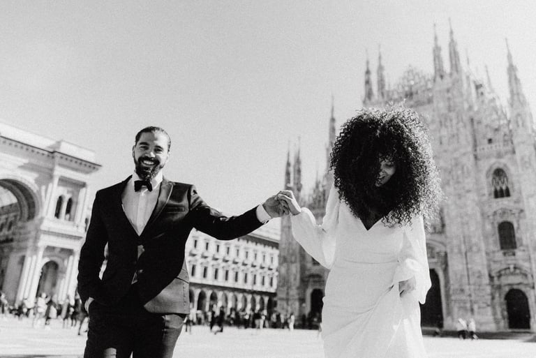 a man and woman holding hands and walking through in Milan Piazza Duomo