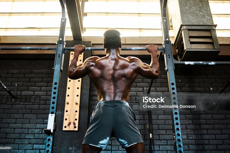 Muscular athlete performing pull-ups on a gym rack to build back muscle strength.
