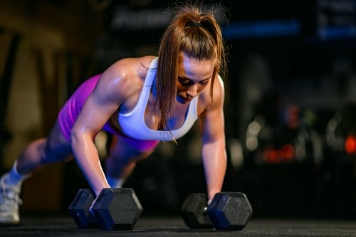 a woman doing pushups on a dumbbell