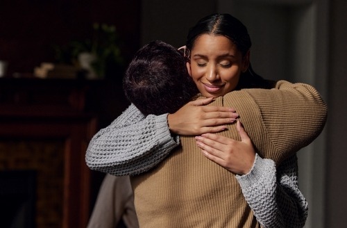 a woman in a sweater is hugging her friend