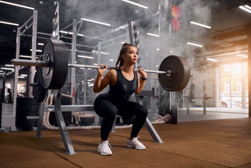 a woman squats on a barbell in a gym
