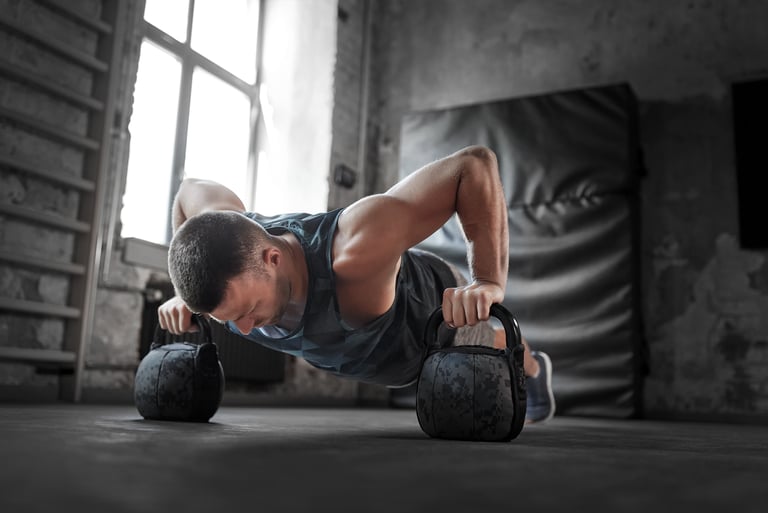 Athletic man performing kettlebell pushups for strength training in a rustic industrial gym.