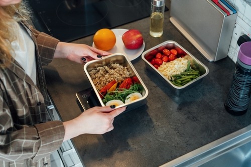 a woman is holding a tray with food in it