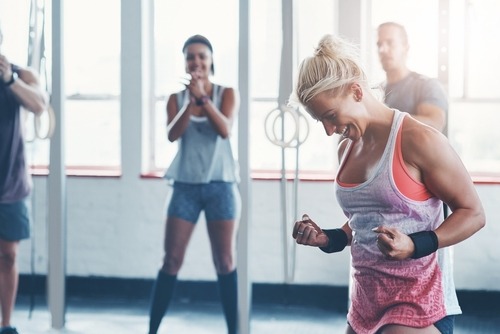 A cheerful woman celebrating a successful crossfit workout in a gym with friends.