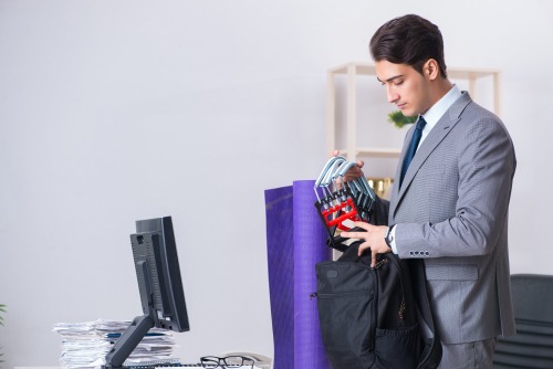 Businessman packing fitness equipment and a yoga mat into a bag for a workout after office work.