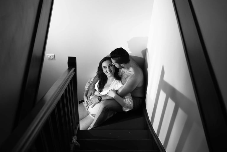 couple assis dans l'escalier pour une photo de grossesse