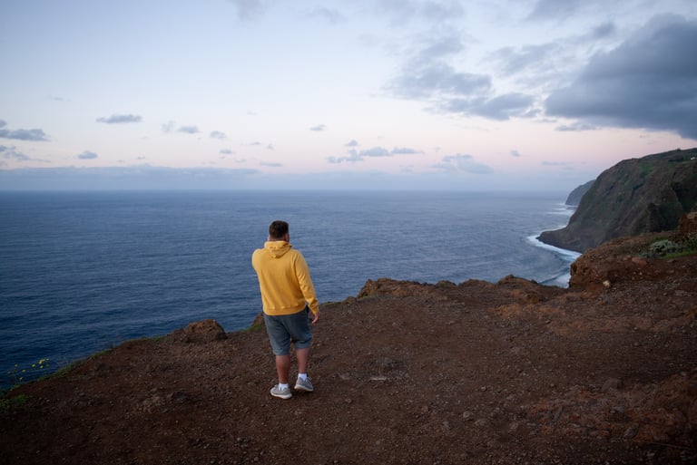 	Man in yellow jacket overlooking Atlantic Ocean at sunset Madeira