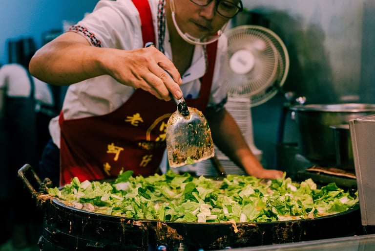 a man in a red apron making Taiwanese Oyster Omelette