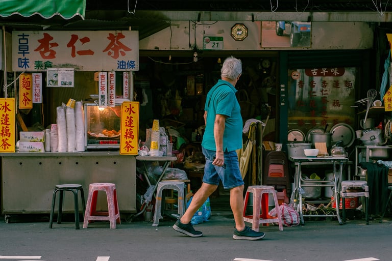 a man walking down the street in front of a Taiwanese street food vendor