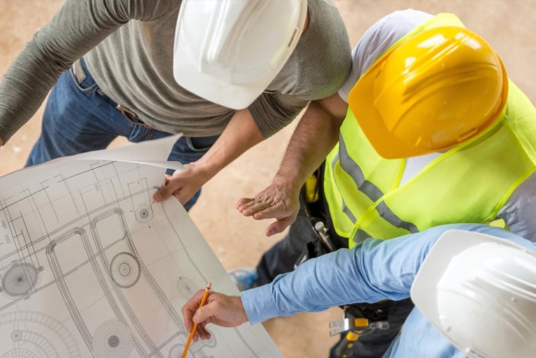 two men in safety vests and helmets standing in front of a building