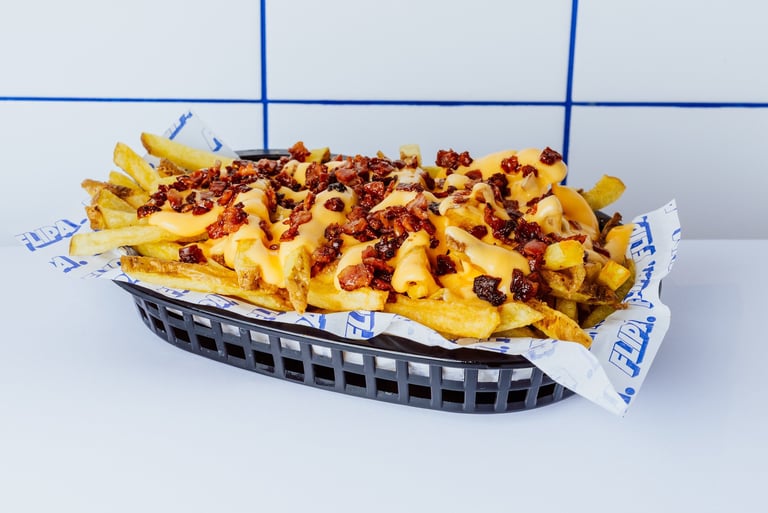Patatas fritas de Flipa cortadas a mano diariamente, con salsa de quesos y bacon bits