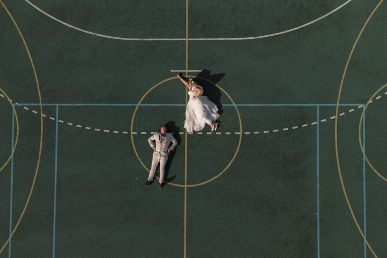 a man and woman holding umbrellas on a basketball court