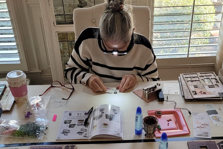 Assembling the DIY book nook kit at a table with miniature pieces and instructions.