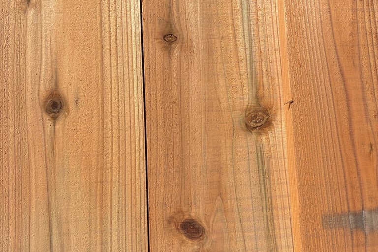 Natural sugi wood planks with visible knots and grain texture for cladding or decking.