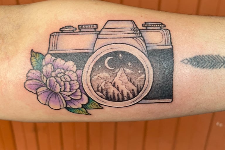 Tattoo of camera with a mountain scenery and flower