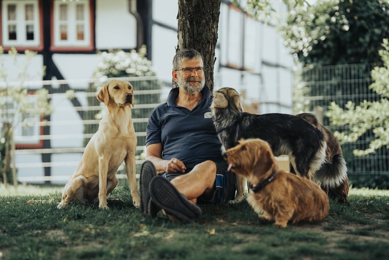 Martin Lindhof im Garten vom Hunde Hotel Hunde Freude mit drei lieben Hunden.