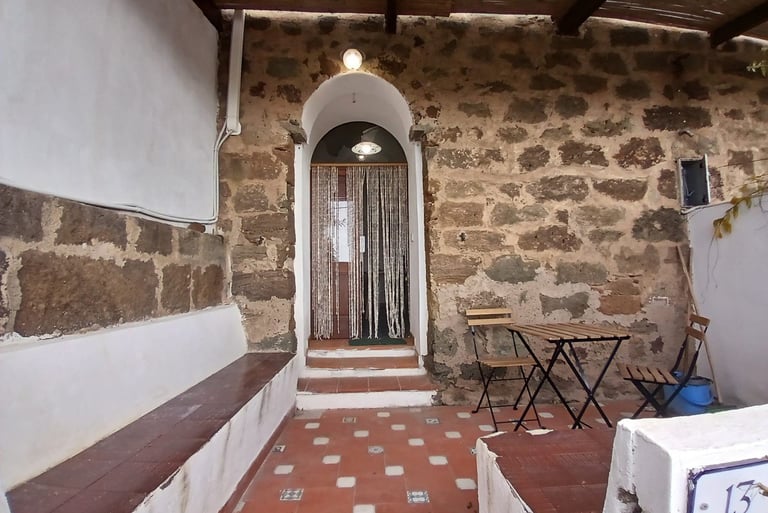 Entrance of a dammuso in Rekhale with stone arch, beaded curtain and tiled patio