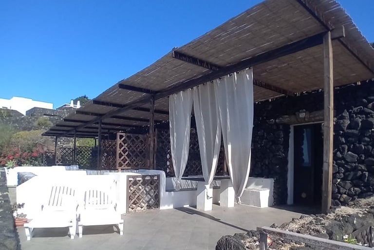 Dammuso in Sataria with white canopy and stone patio near the Sataria cave