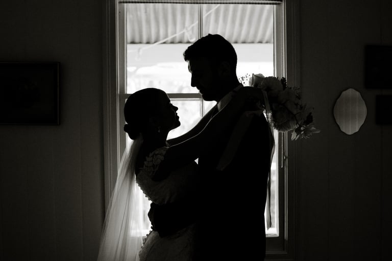 a bride and groom standing in front of a window