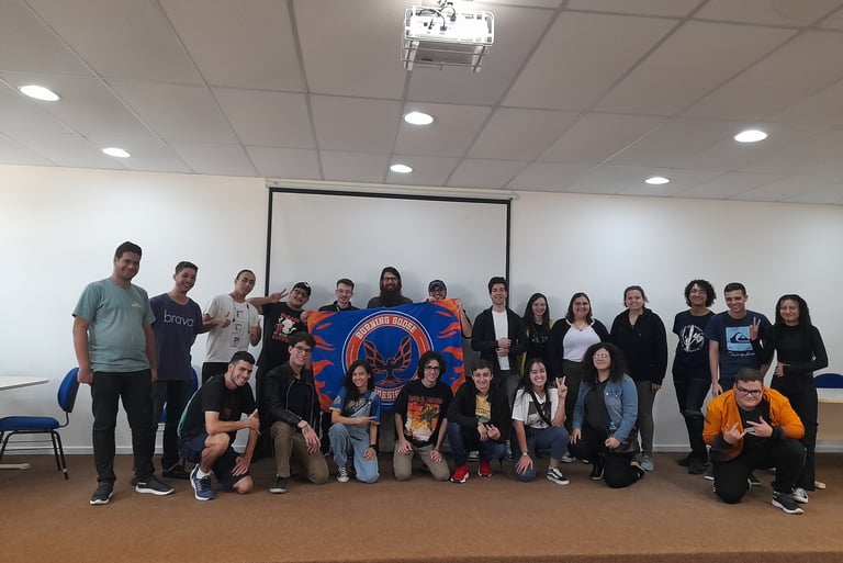 Membros da equipe pousando para a foto na frente da bandeira da equipe