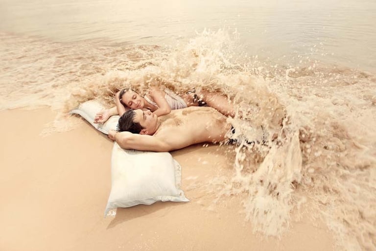 a man and woman laying on a pillow on Samui beach