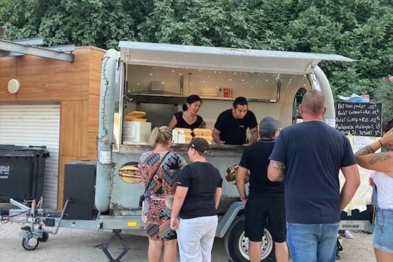 a group of people standing around a food truck
