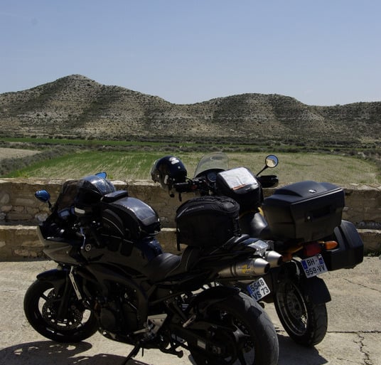 a motorcycle parked on a concrete surface with a mountain in the background