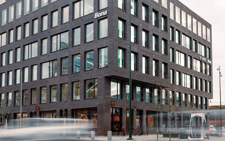 Modern dark brick Bona office building with large windows on a city street corner.
