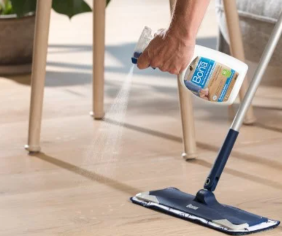 a person cleaning a wooden floor with a mop