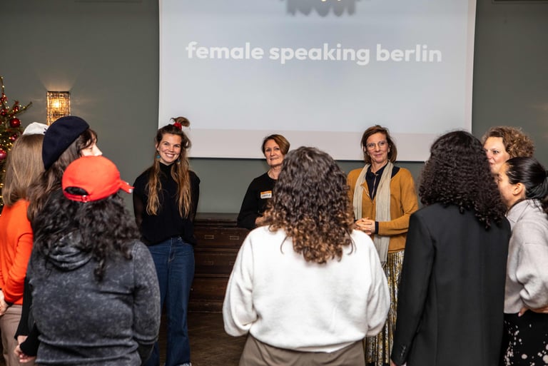 Women in circle, smiling and listening to each other, in workshop room, beamer logo female speaking 