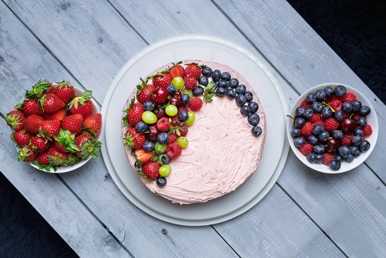 a cake with fruit on a table with bowls of fruit