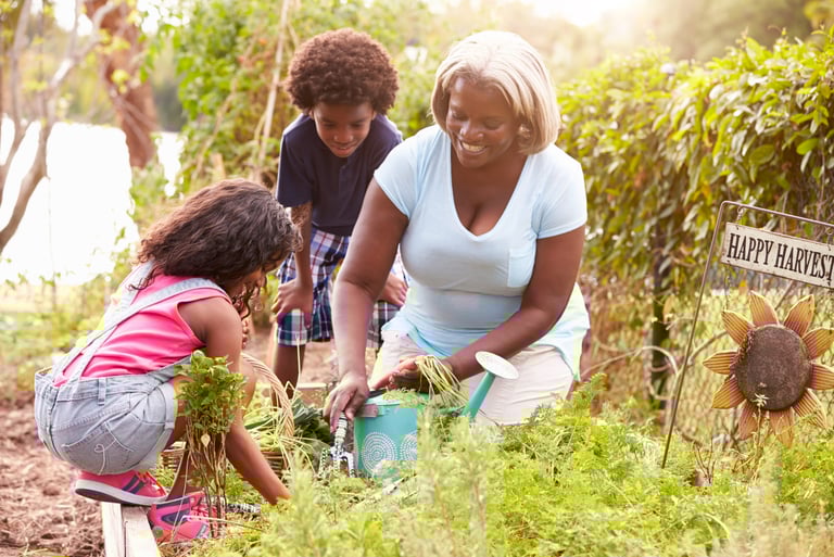 Una mujer afro con dos crios en un jardin