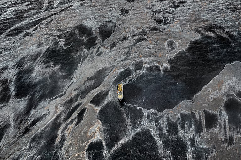 Edward Burtysnsky "Oil" a boat is floating in the water with petroleum