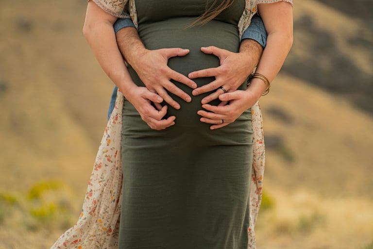 Mujer embarazada acariciando su vientre mientras su pareja la abraza