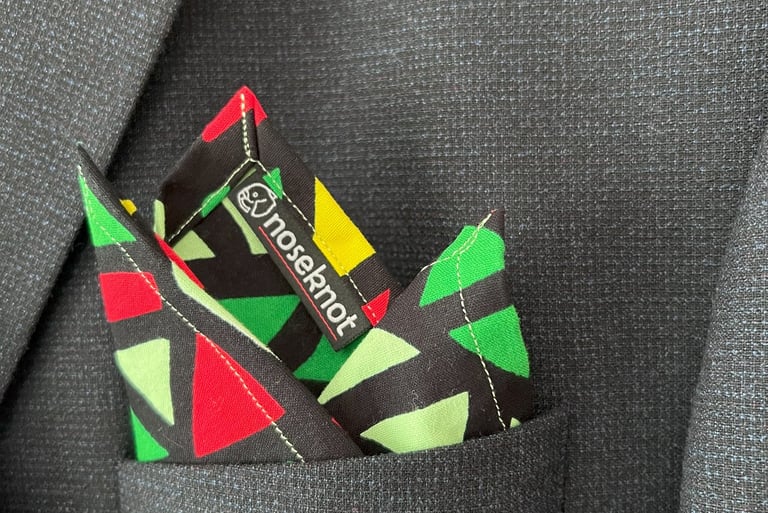 A Noseknot handkerchief showing the Noseknot logo in a suit pocket