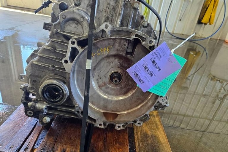 Used car transmission assembly with purple identification tag on a wooden pallet.