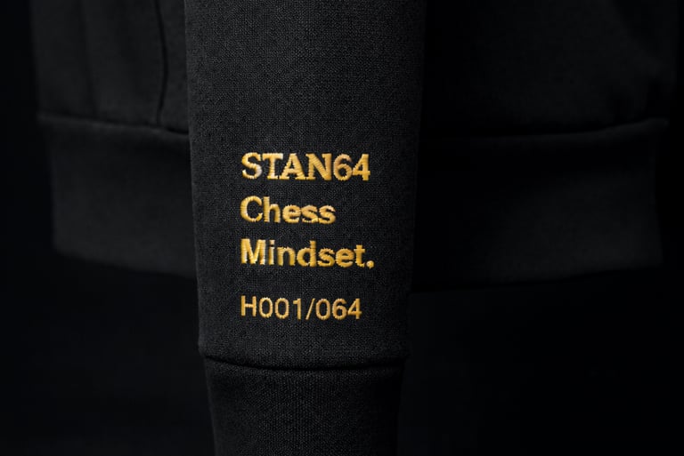 STAN64 Black hoodie sleeve featuring gold embroidered Chess Mindset text and serial number.