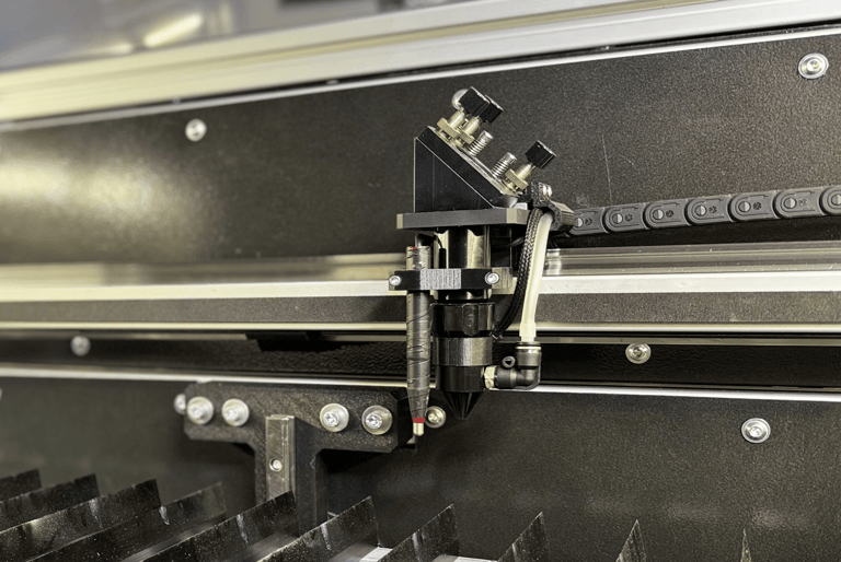 Zdjęcie wnętrza lasera CO2, przedstawia stół nożowy oraz głowicę 