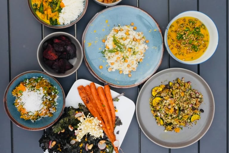 a table with bowls of vegetarian plant-based food and a bowl of vegetables carrots chickpeas