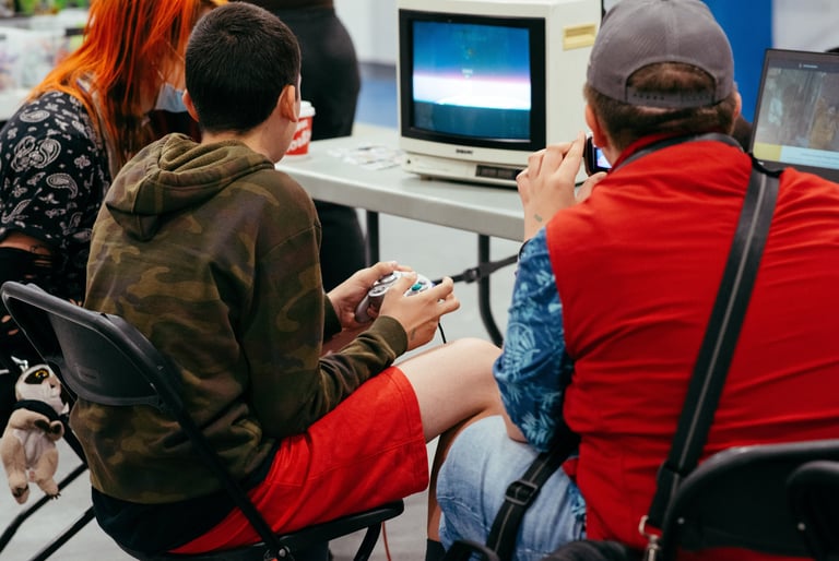 Close up image of two people sitting at an old tv playing some video games together at the event.