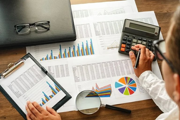 a person sitting at a desk with a calculator and a magnifying