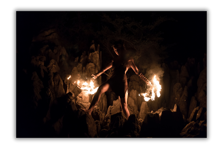 a woman in a black dress is holding a fire