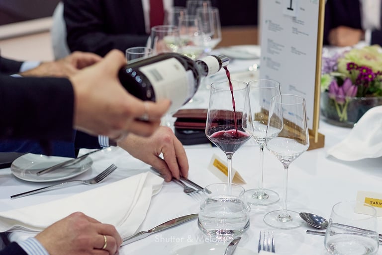 Der Kellner schenkt Rotwein in ein Glas ein.