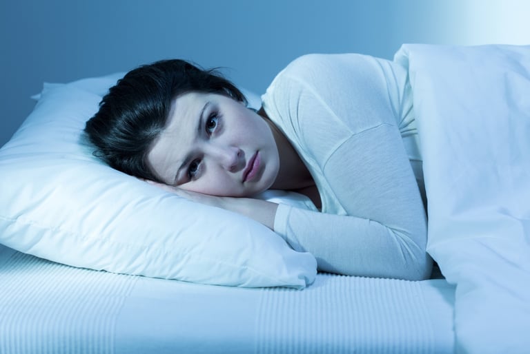 Woman lying awake at night feeling emotionally drained, anxious and affected by a heavy environment