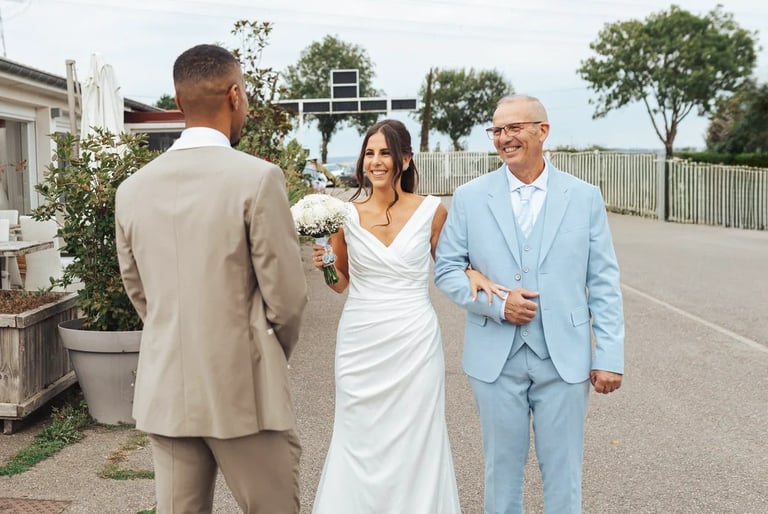 Découverte des mariés : la mariée arrive au bras de son père, souriante, face à son futur époux.